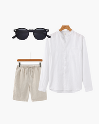 Lookbook flat-lay: white mandarin-collar linen shirt, beige drawstring shorts and black round sunglasses
