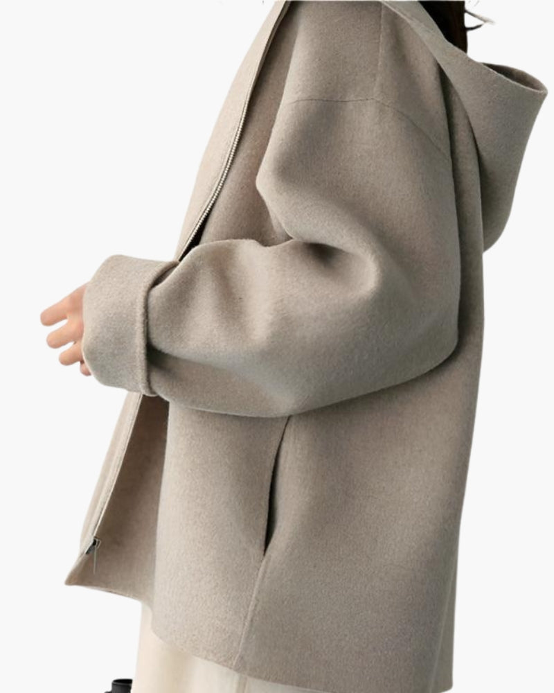Side view of woman wearing beige hooded coat, hands in pockets