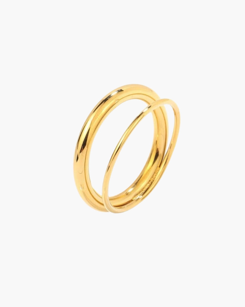 Anillo doble dorado con dos bandas entrelazadas, en plano sobre blanco