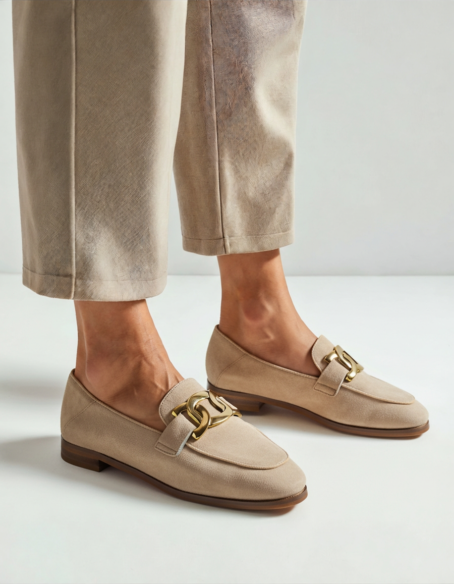 Beige suede loafer with gold chain trim, three-quarter view, worn with stone trousers
