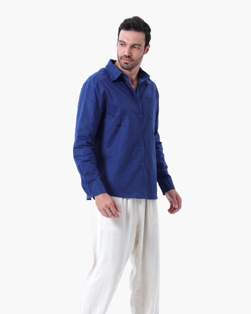 Man in a royal blue linen shirt with chest pocket and white trousers, three-quarter view