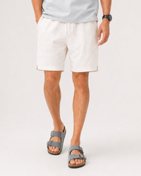 Man in white drawcord tennis shorts with grey sandals and a grey tee, front view