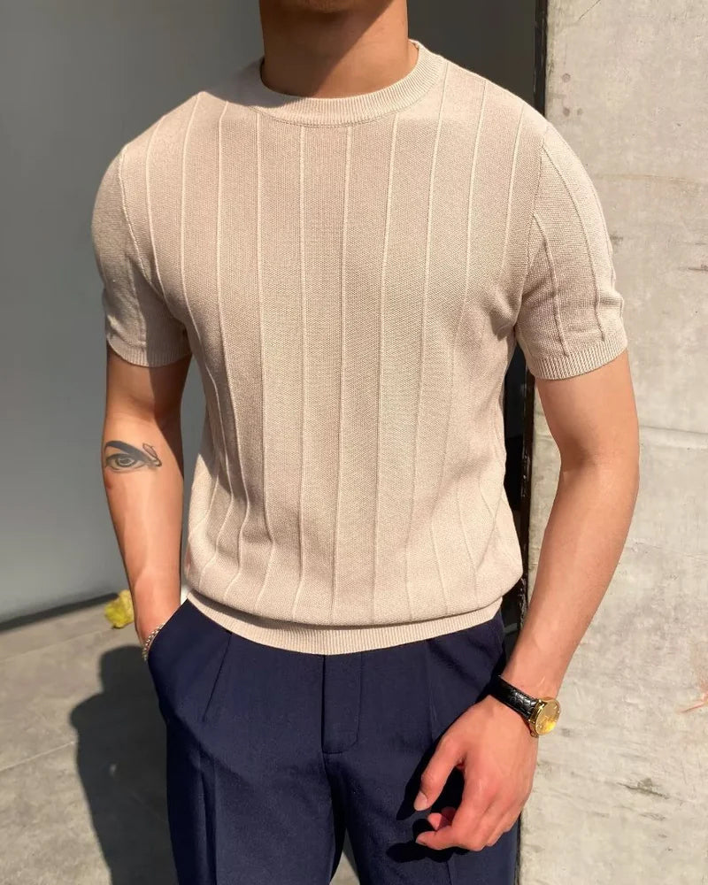 Man in a beige ribbed knit crewneck tee with navy trousers outdoors