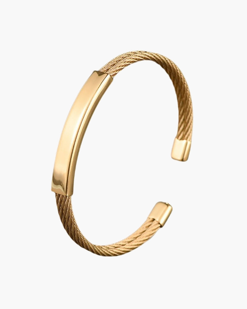 Gold-tone open cuff bracelet with twisted cable sides and flat engravable plate, flat-lay
