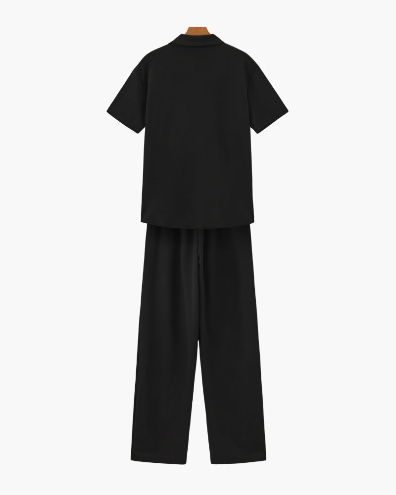 Back view of a black short-sleeve polo and wide-leg trousers set on hangers