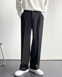 Man wearing black pleated wide-leg trousers with white sneakers, white knit top