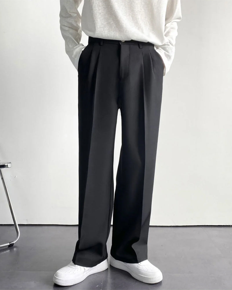 Man wearing black pleated wide-leg trousers with white sneakers, white knit top