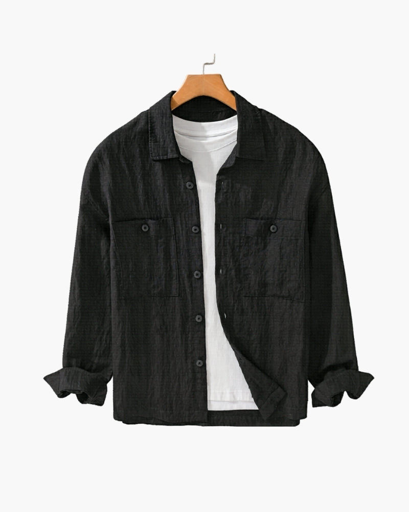 Black crinkled linen overshirt with two chest pockets, open over a white tee, on a wooden hanger