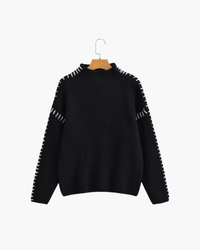 Black oversized jumper with white whipstitch seams and funnel neck, on a hanger, front view
