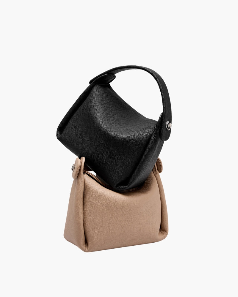 Small leather top-handle handbags in black and beige, stacked, with silver side studs