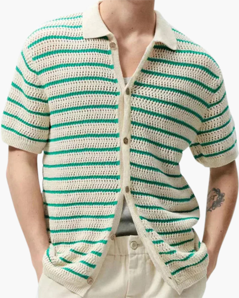 Man wearing cream and green striped open-knit shirt, buttoned, hands in beige trousers