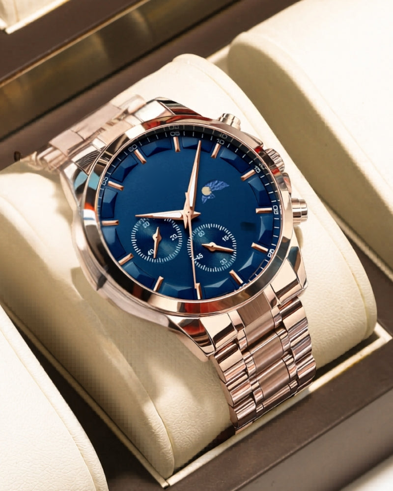 Rose-gold chronograph watch with blue dial resting on a cream watch-box cushion, angled view