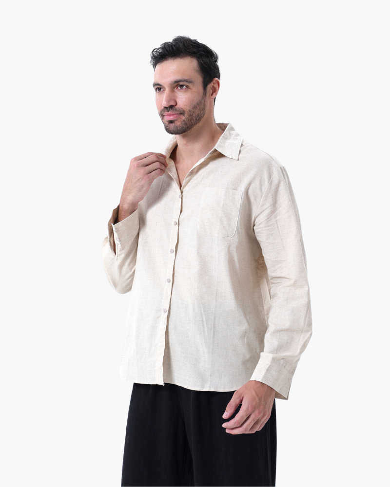 Man in a cream linen shirt over black trousers, hand at collar