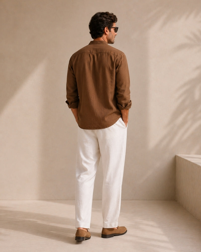 Back view of man in brown mandarin collar shirt, sleeves rolled, white trousers and loafers