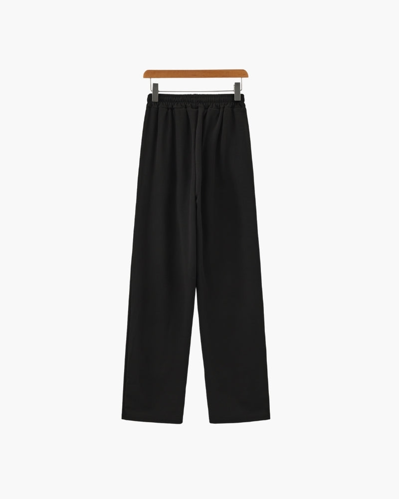 Black wide-leg drawstring trousers with elasticated waist on a hanger, front view