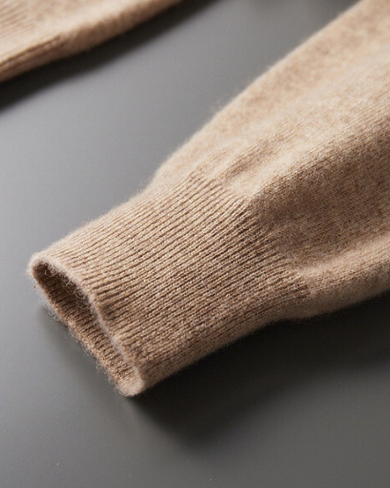 Close-up of a camel cashmere cuff with ribbed knit trim on a grey surface