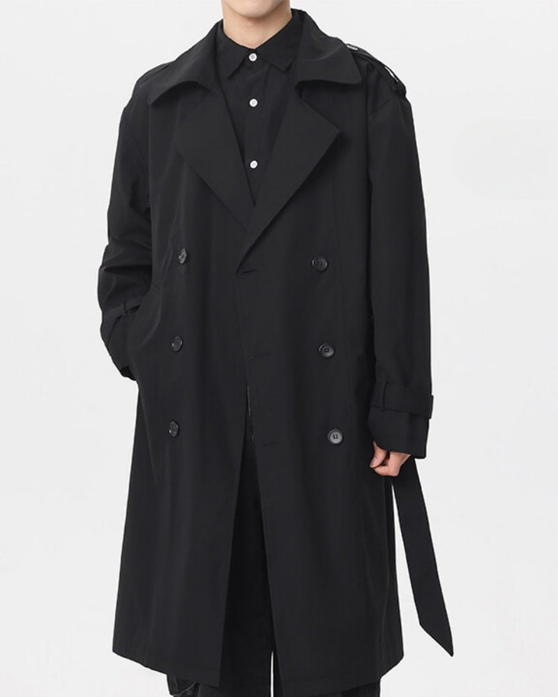 Man in a black belted trench coat worn open with a dark shirt, front view