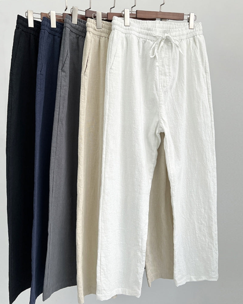 Pantalones de lino con cordón en negro, azul marino, gris, avena y blanco colgados en perchas de pinza
