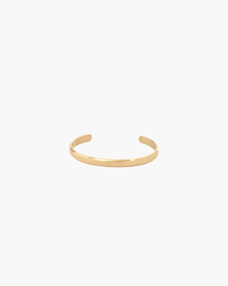 Gold-tone polished open cuff bracelet with a slim flat band, front view on white