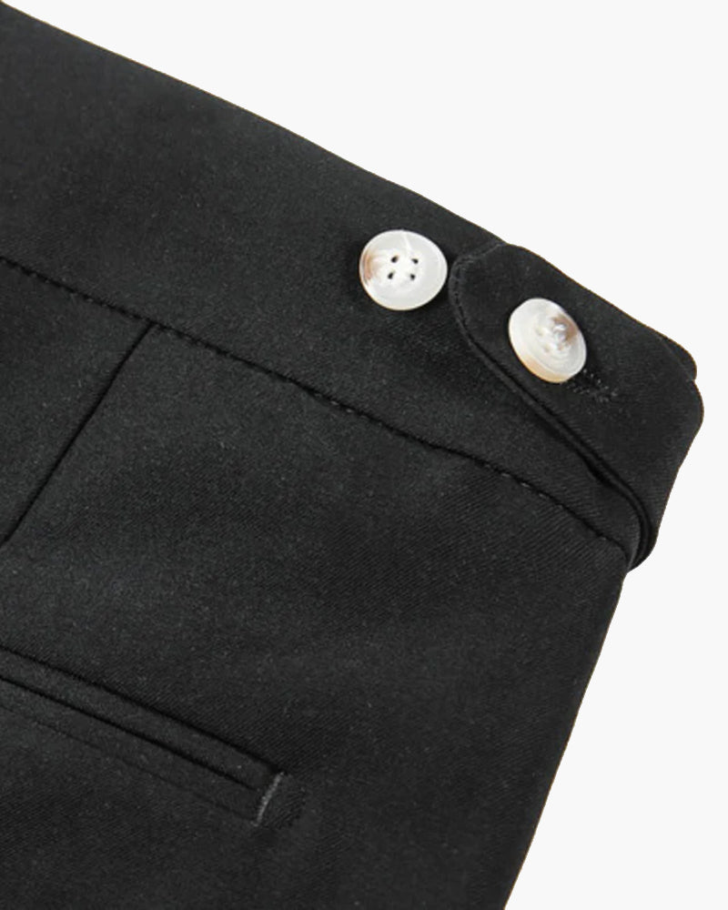 Primer plano del ajustador lateral de unos shorts negros con dos botones efecto perla y bolsillo inclinado