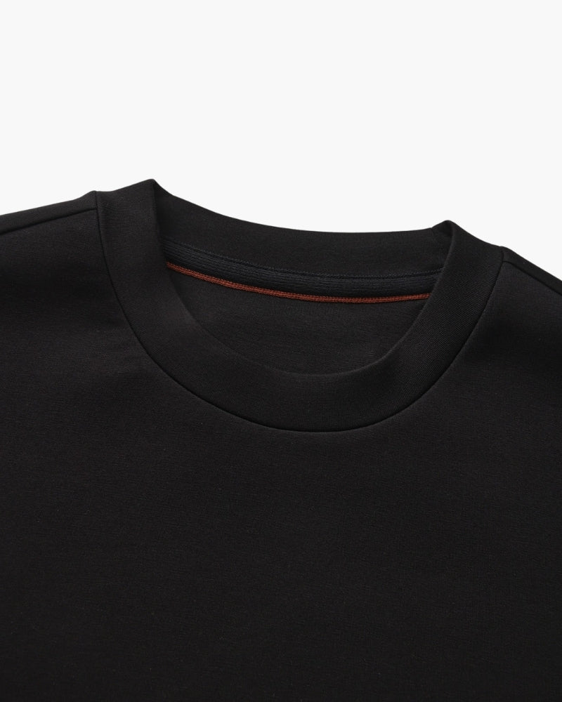 Gros plan sur l'encolure ronde d'un sweat noir avec ruban intérieur couleur rouille