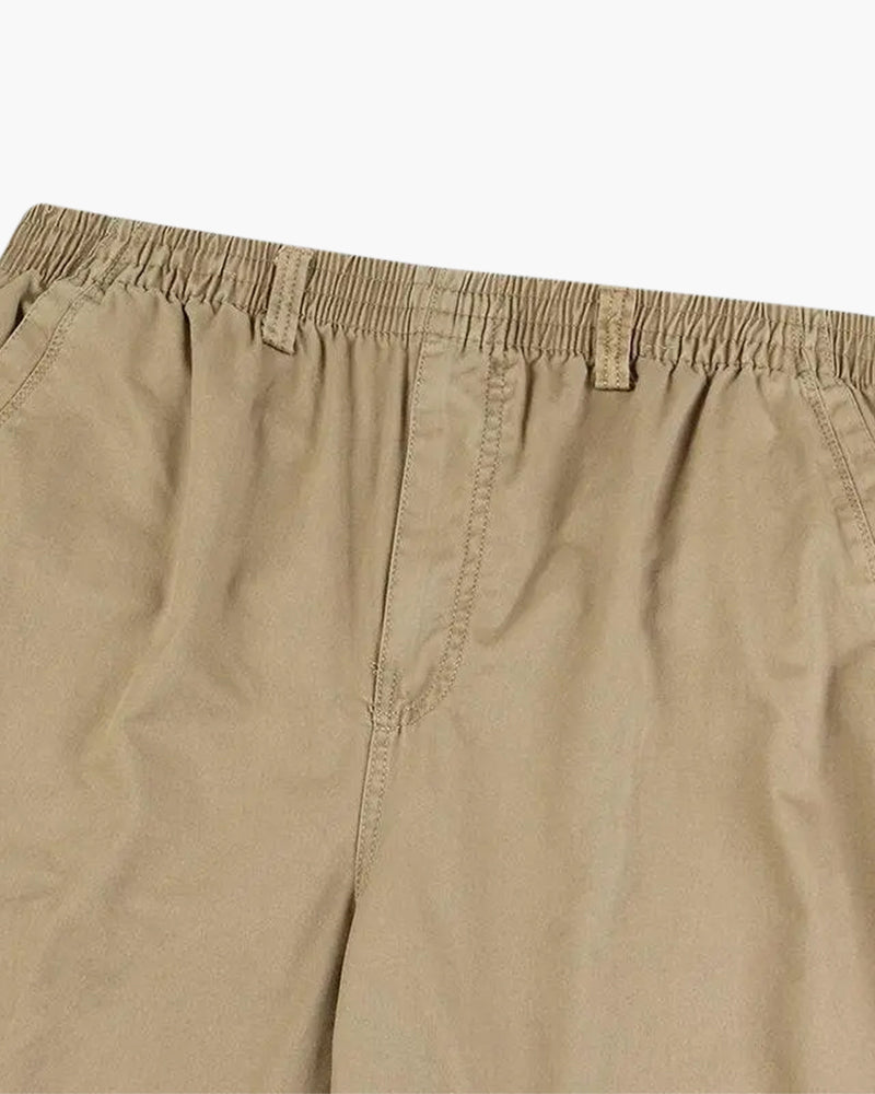 Close-up of khaki trousers' elastic waist and front fly detail, flat on white
