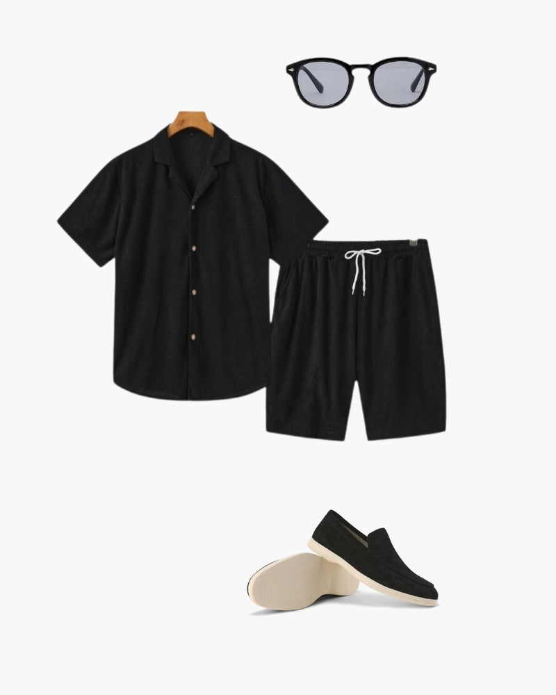 Black textured camp-collar shirt and drawstring shorts set with sunglasses and black loafers, flat-lay