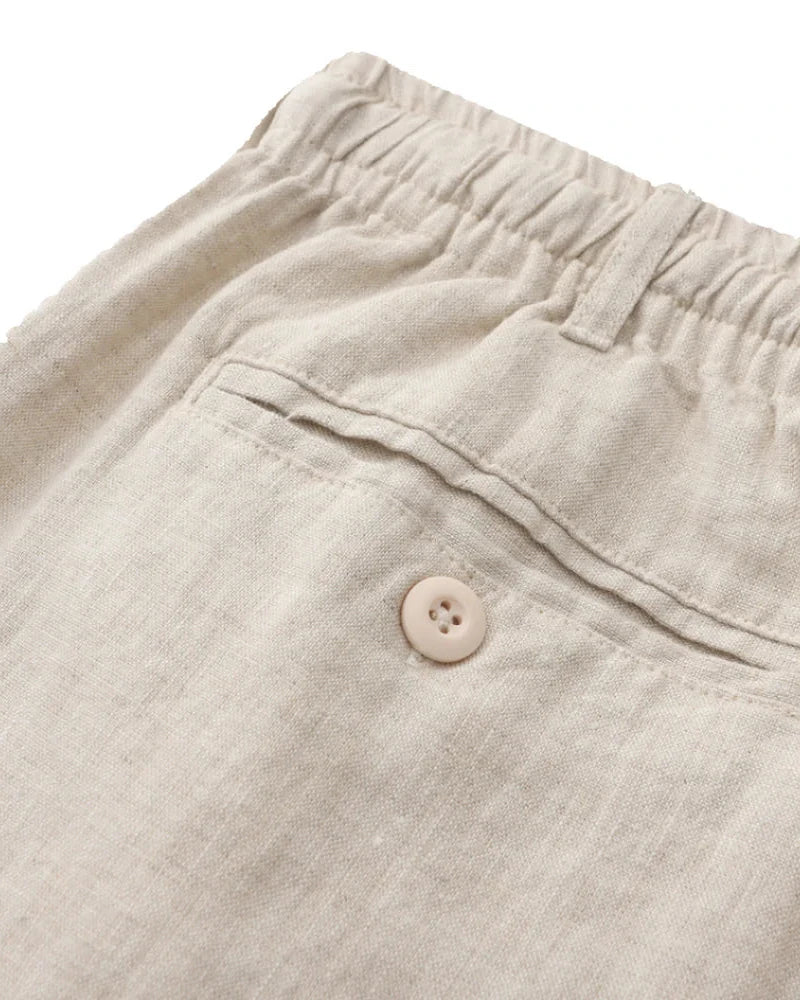 Close-up of natural linen shorts back pocket with button and elastic waist