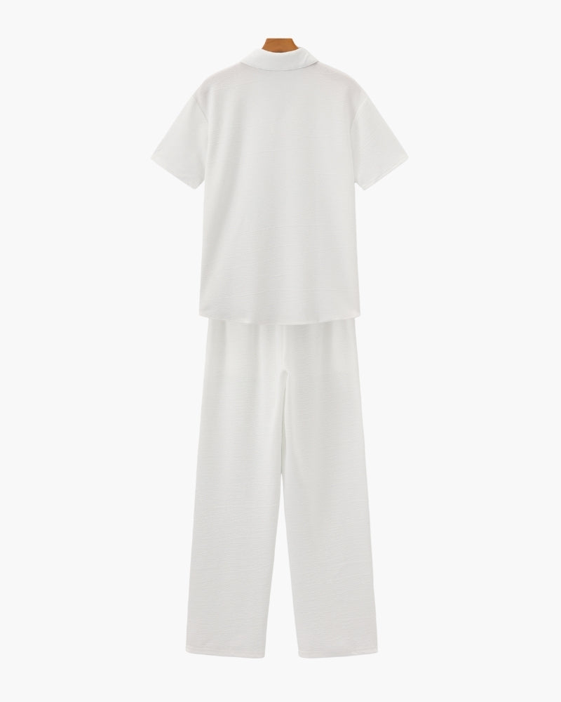 Back view of a white short-sleeve polo and wide-leg trousers set on hangers
