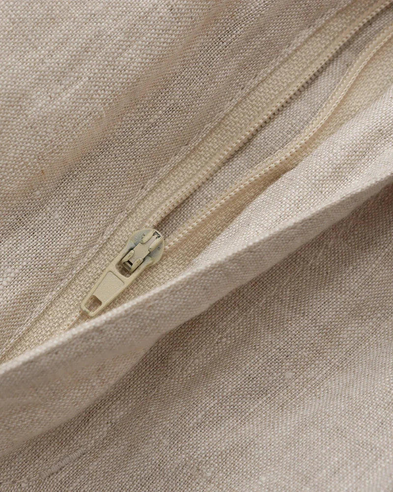 Close-up of natural linen shorts fly zip with cream puller and woven texture