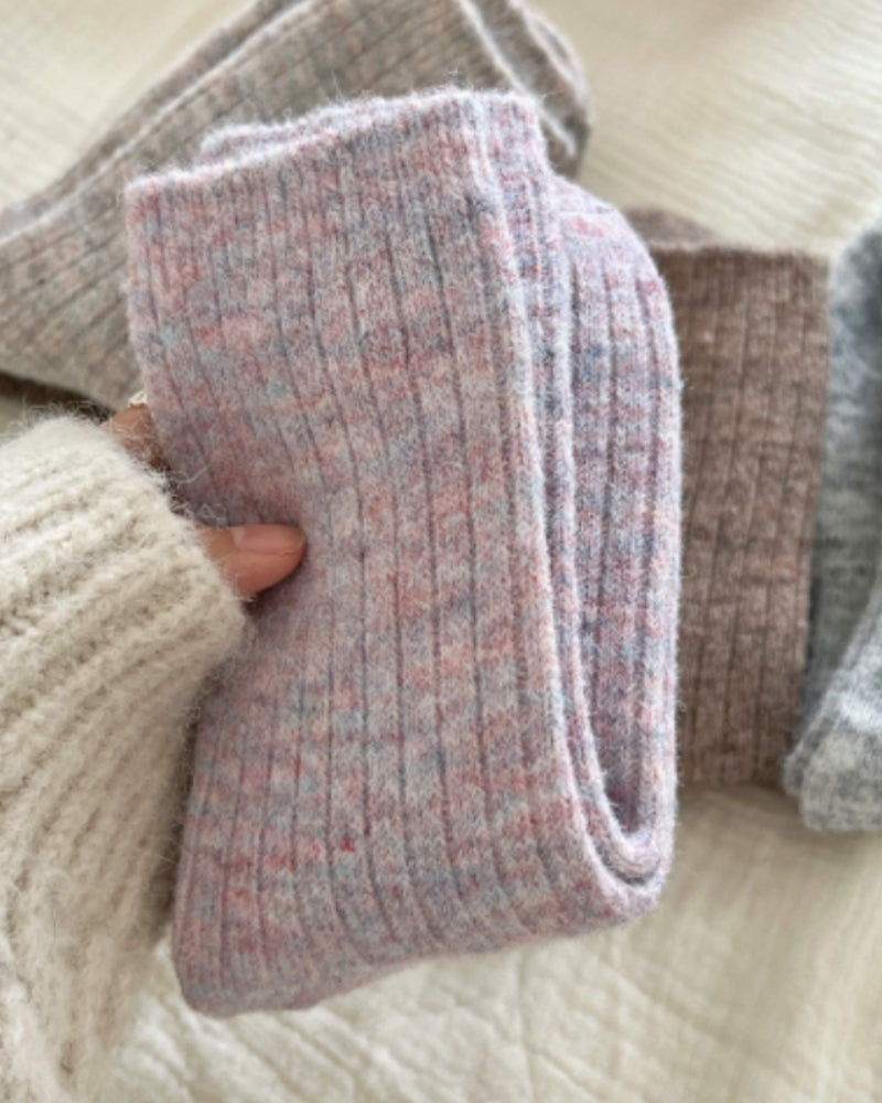 Close-up of a lilac-pink ribbed cashmere sock held in hand, with other colours beside it