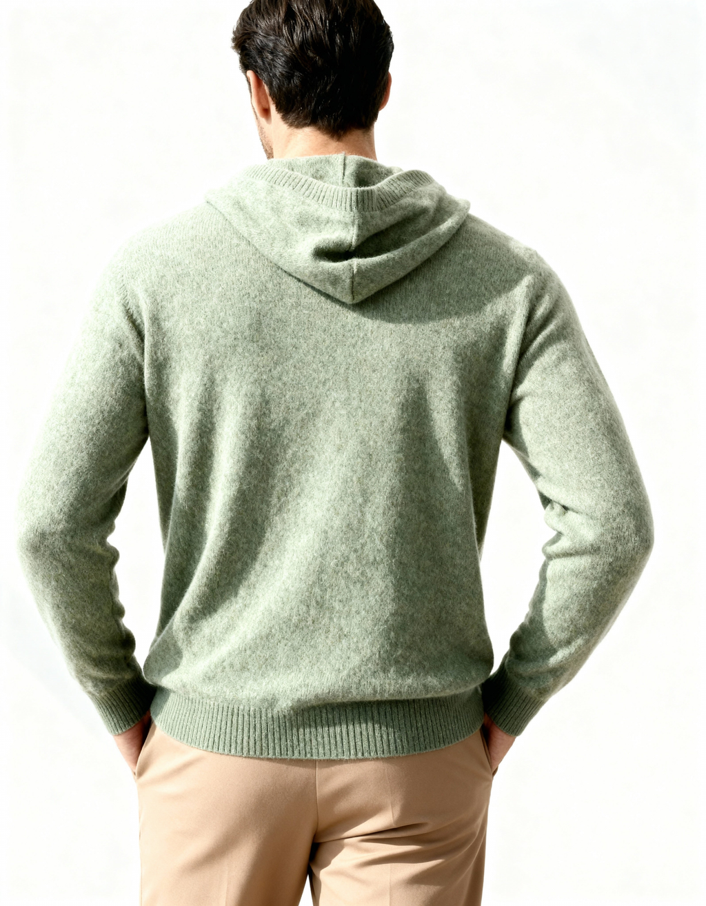 Back view of a sage green cashmere hoodie with hood and ribbed hem, on model