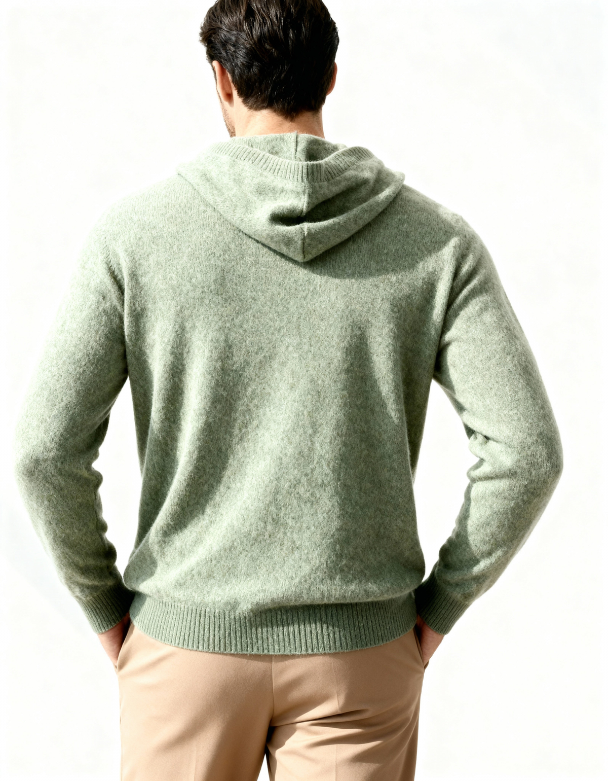 Back view of a sage green cashmere hoodie with hood and ribbed hem, on model