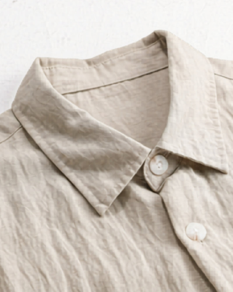 Close-up of beige linen overshirt collar and shell buttons showing the crinkled texture
