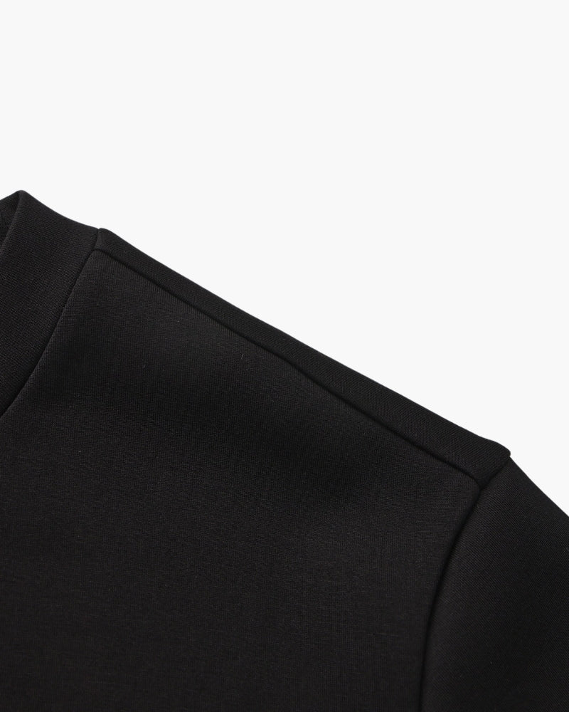 Gros plan sur la couture d'épaule et la manche d'un sweat noir, à plat sur fond blanc