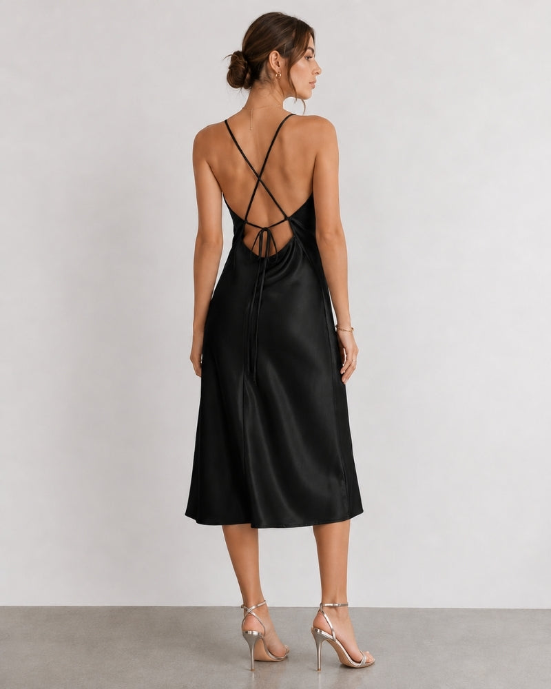 Vue de dos d'une femme en robe nuisette en satin noir à bretelles croisées et sandales à talons