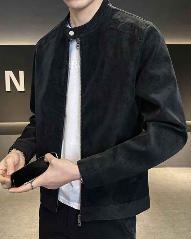 Man wearing black suede-look zip jacket over white tee, holding a phone