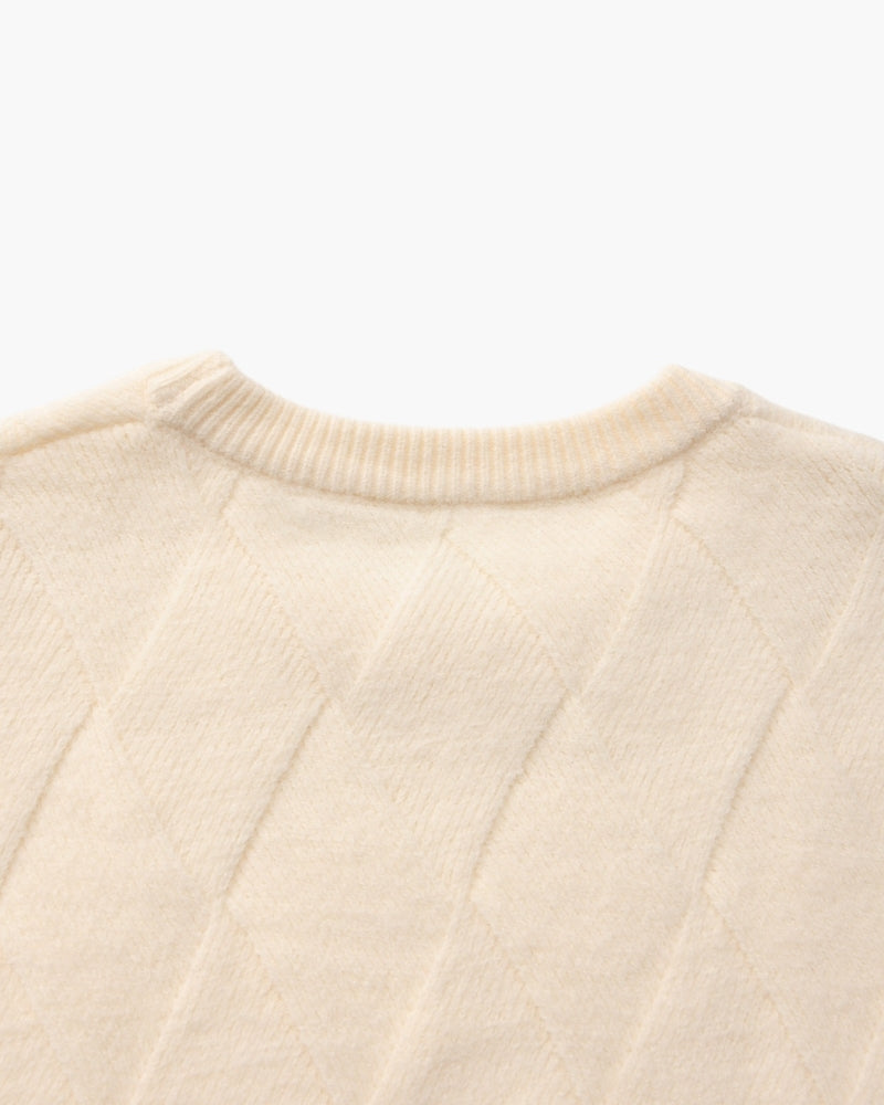 Gros plan sur le dos de l'encolure d'un pull crème en maille losange