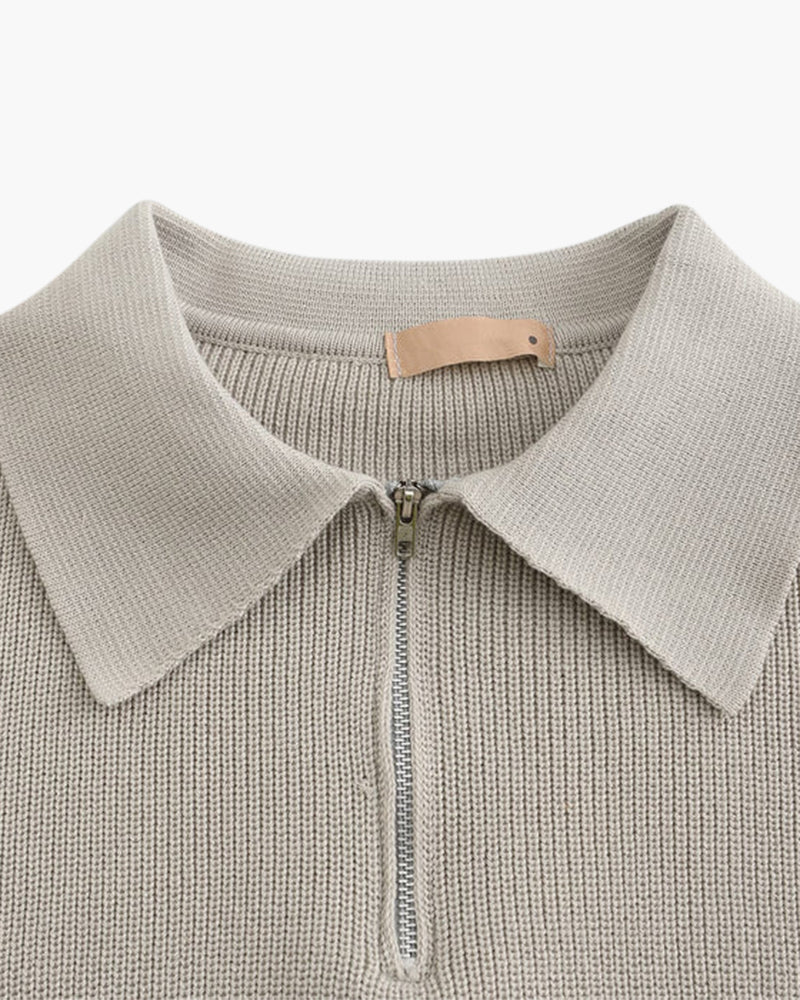 Close-up of stone grey half-zip jumper collar, zip and leather tab