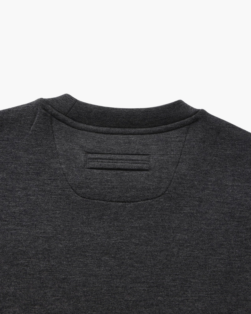 Gros plan sur l'empiècement de nuque et la patte d'un sweat col rond anthracite