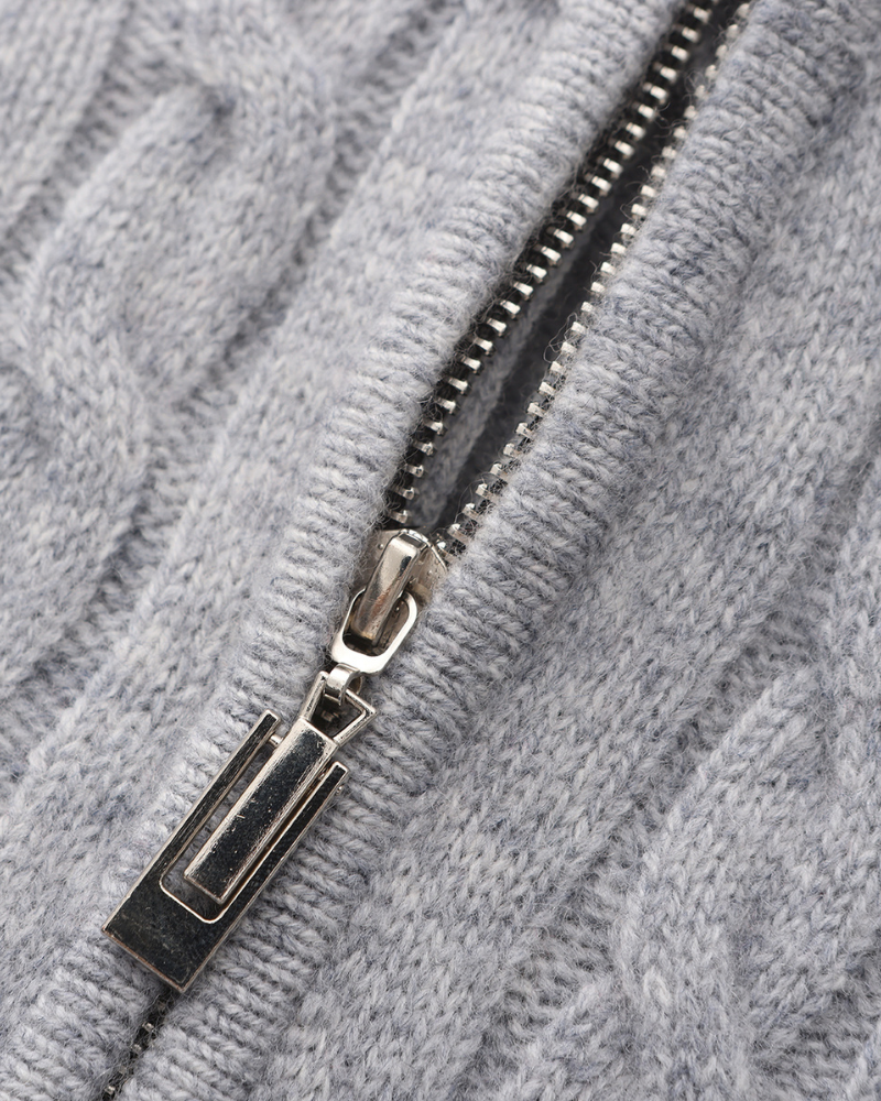 Close-up of a silver zip on a light grey cable-knit cashmere jumper