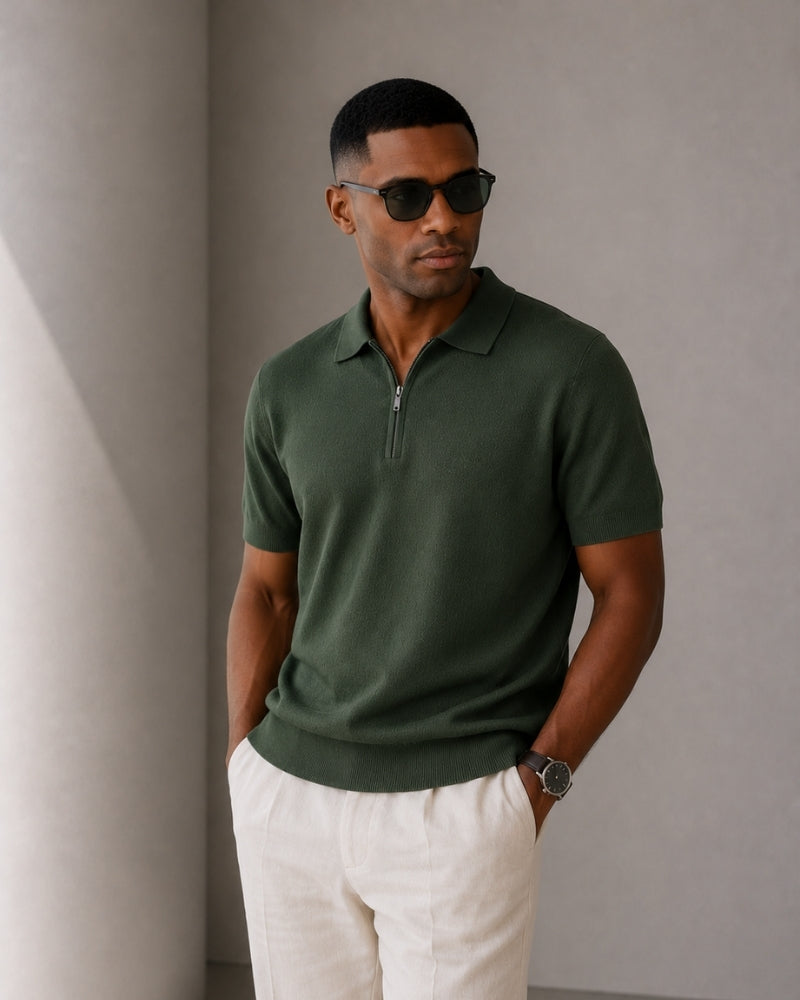 Man in sunglasses wearing dark green knit zip polo and cream trousers