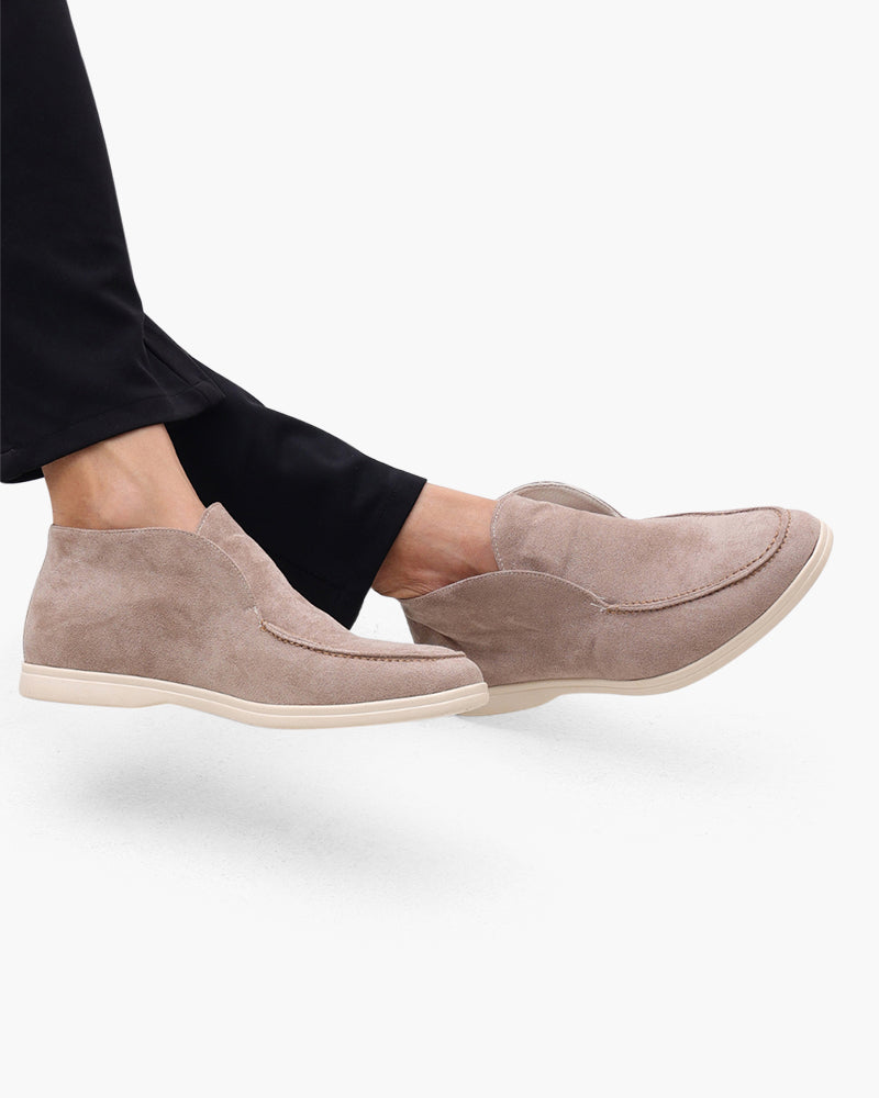Taupefarbene Wildleder-Stiefeletten mit cremefarbenen Sohlen zu marineblauer Hose, Beine überschlagen, Seitenansicht