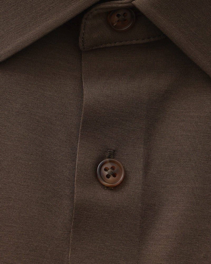 Close-up of dark brown shirt placket and horn-effect four-hole button