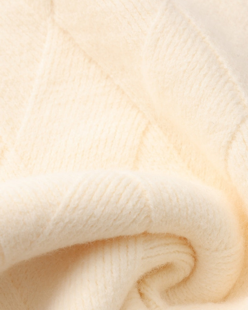 Macro d'une maille losange crème douce en laine mélangée pliée pour montrer la texture