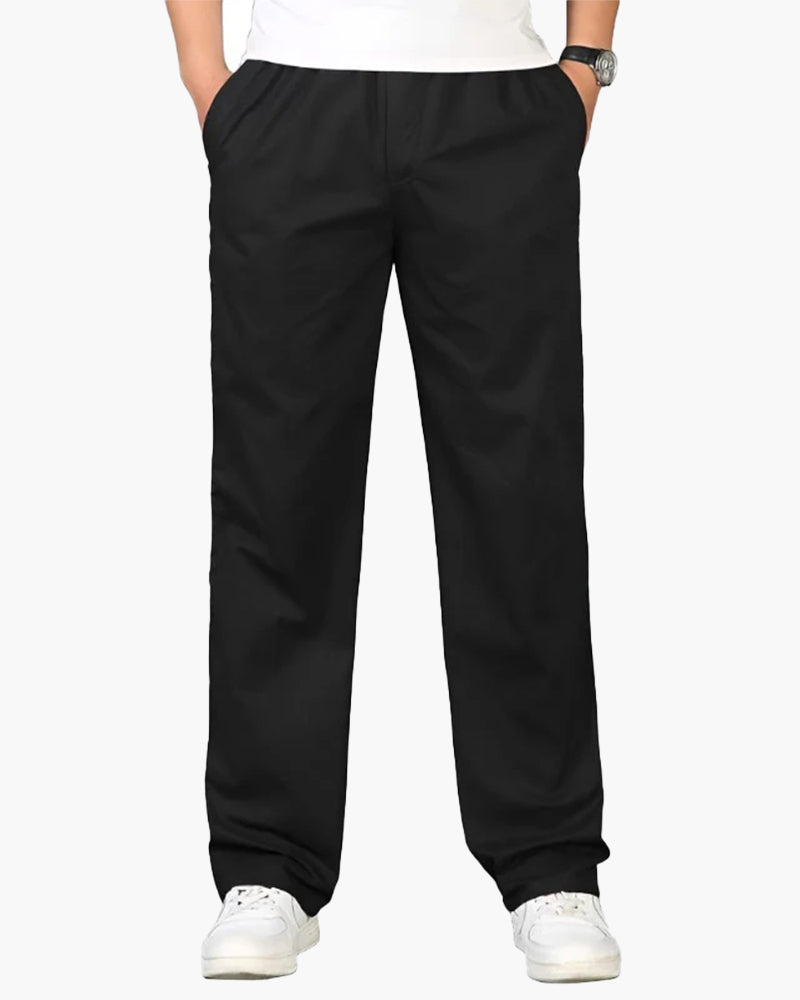 Man in black straight cotton-linen trousers with elastic waist and white trainers