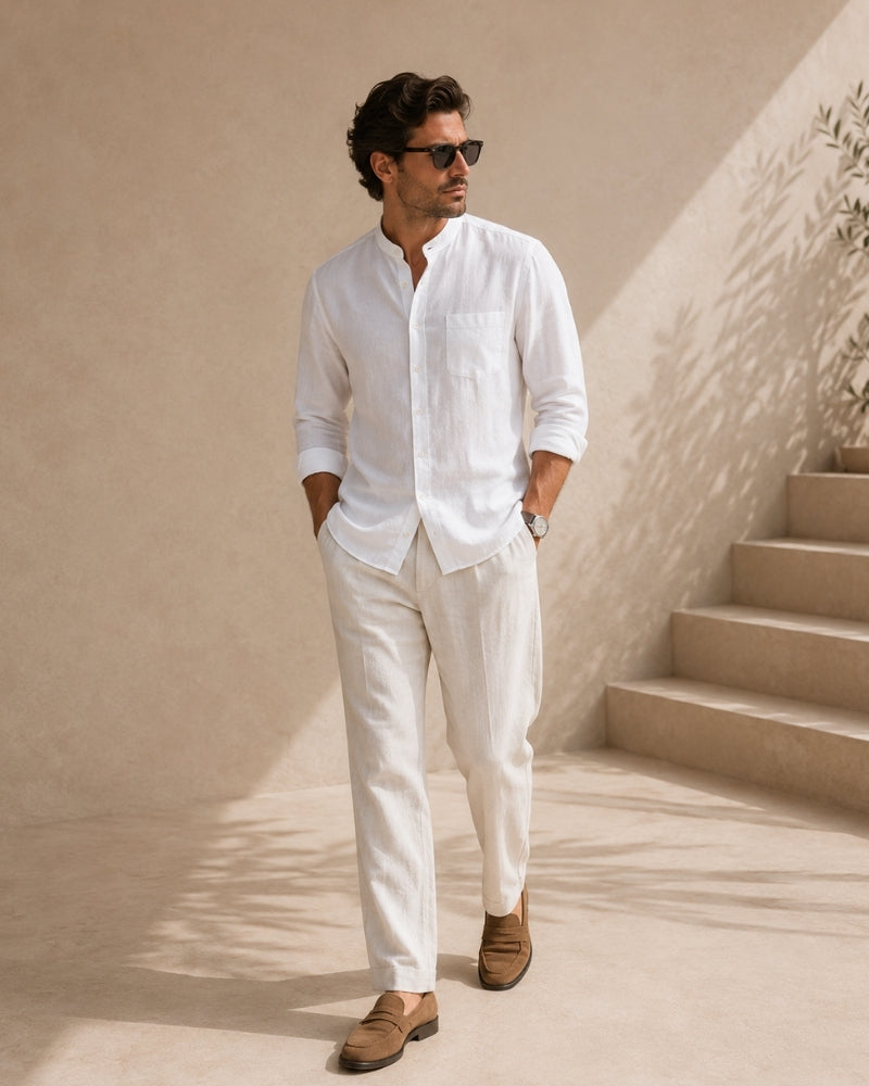 Man in sunglasses wearing white mandarin collar shirt and white trousers by steps