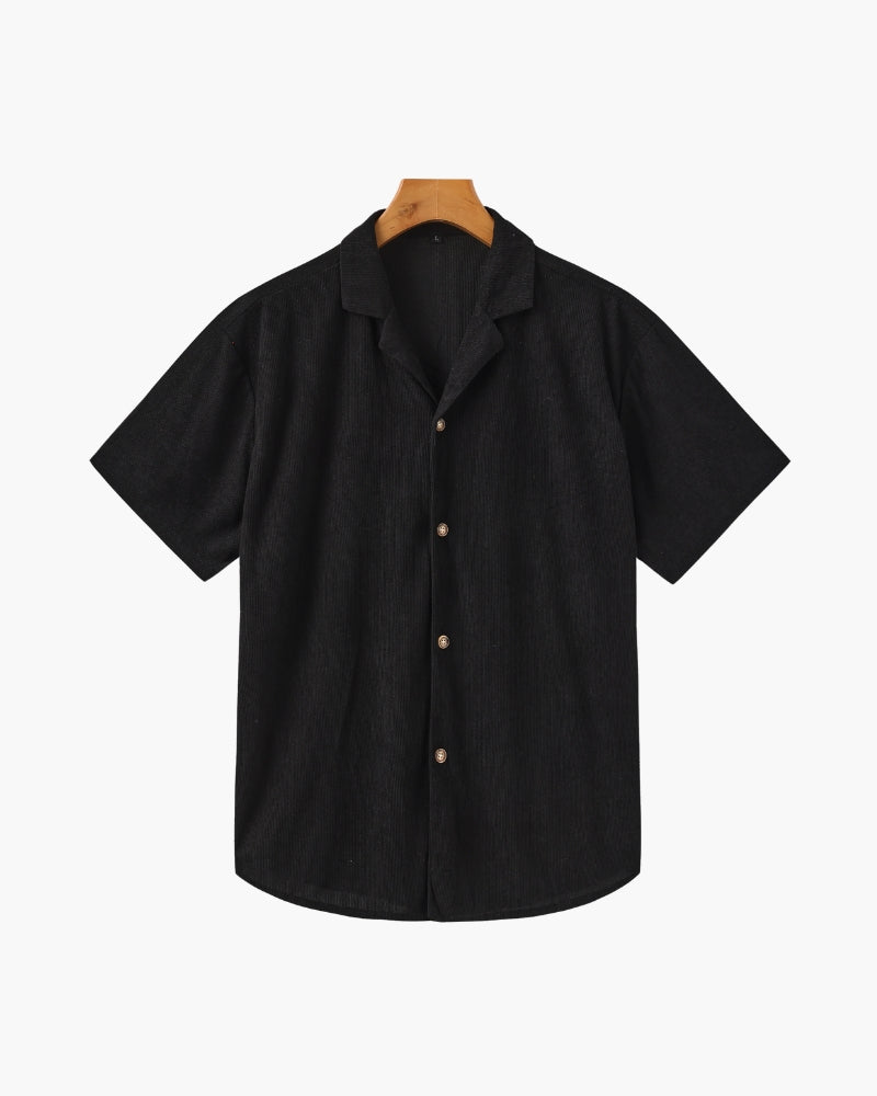 Black textured camp-collar short-sleeve shirt with horn-effect buttons on a hanger, front view
