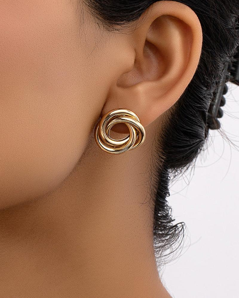 Oreja de una mujer con pendiente de botón de nudo entrelazado dorado, vista lateral
