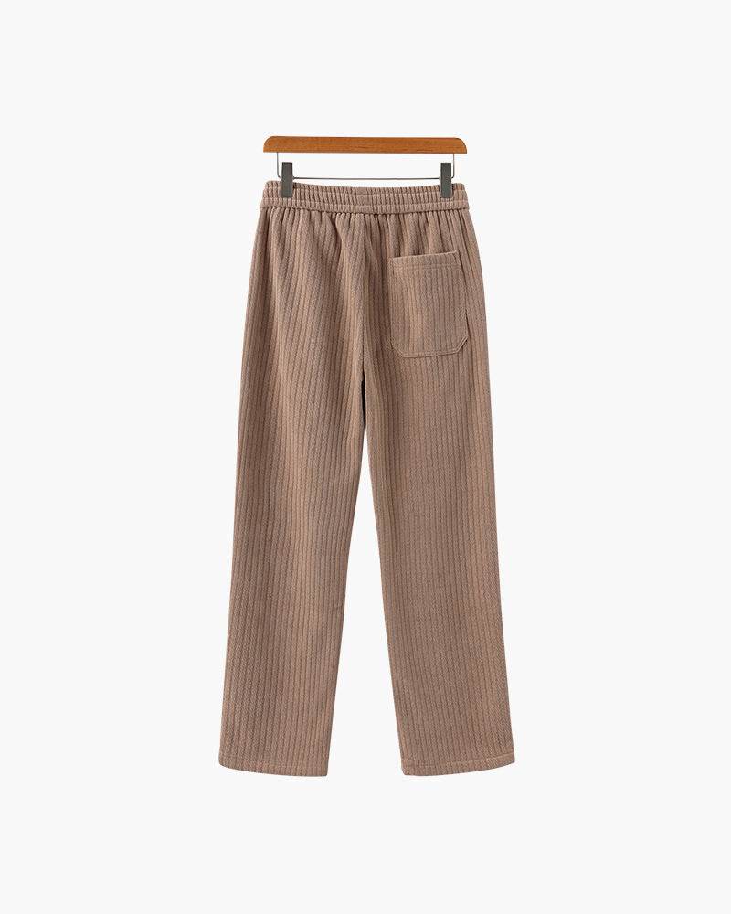 Back view of taupe-brown ribbed velvet trousers with patch back pocket, on a wooden hanger